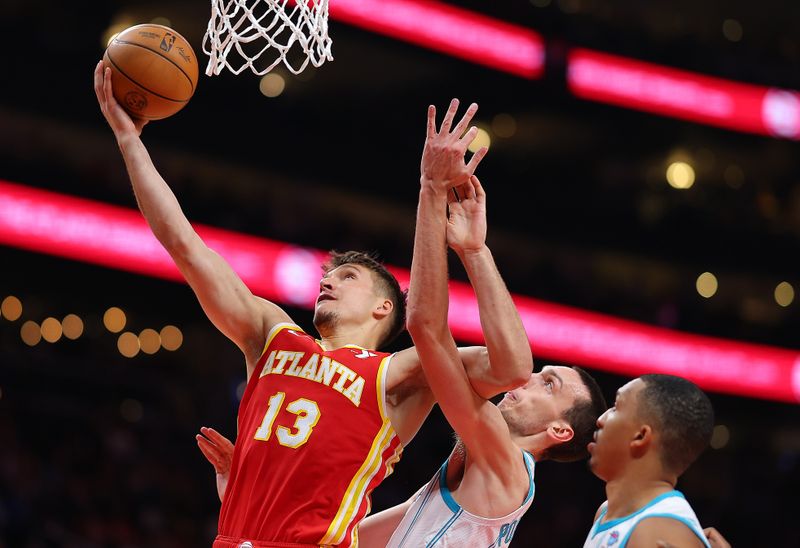 ATLANTA, GEORGIA - APRIL 10:  Bogdan Bogdanovic #13 of the Atlanta Hawks attacks the basket against Aleksej Pokusevski #17 and Grant Williams #2 of the Charlotte Hornets during the second quarter at State Farm Arena on April 10, 2024 in Atlanta, Georgia.  NOTE TO USER: User expressly acknowledges and agrees that, by downloading and/or using this photograph, user is consenting to the terms and conditions of the Getty Images License Agreement.  (Photo by Kevin C. Cox/Getty Images)