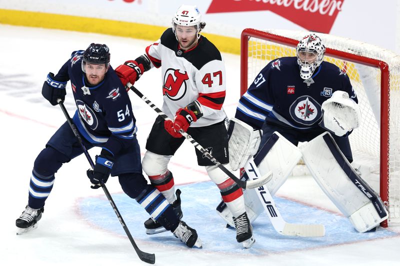 Jan 11, 2026; Winnipeg, Manitoba, CAN; Winnipeg Jets defenseman Dylan Samberg (54), New Jersey Devils left wing Paul Cotter (47) and Winnipeg Jets goaltender Connor Hellebuyck (37) watch a play develop during the third period at Canada Life Centre. Mandatory Credit: James Carey Lauder-Imagn Images