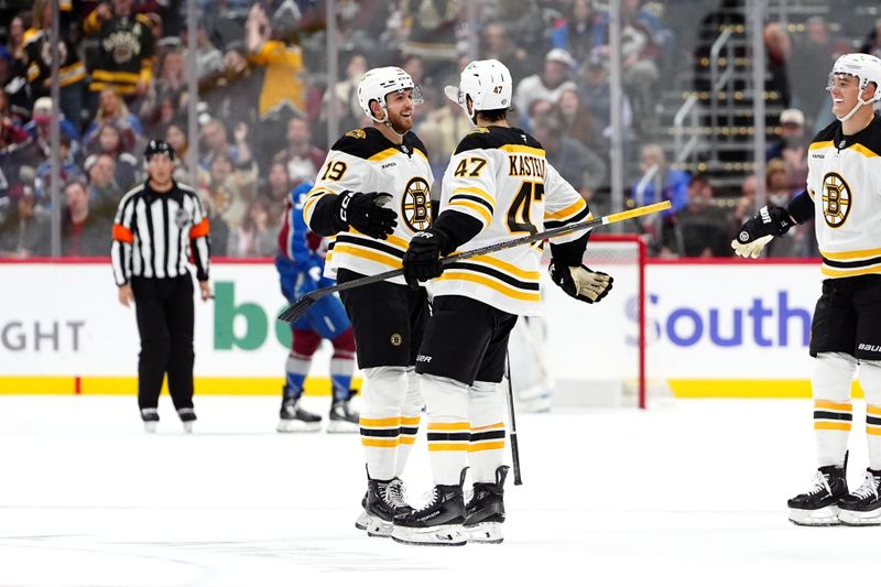 Oct 16, 2024; Denver, Colorado, USA; Boston Bruins center John Beecher (19) celebrates his empty net goal with center Mark Kastelic (47) in the third period against the Colorado Avalanche at Ball Arena. Mandatory Credit: Ron Chenoy-Imagn Images