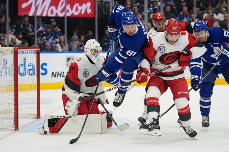 Nov 9, 2025; Toronto, Ontario, CAN; Toronto Maple Leafs forward Dakota Joshua (81) gets out of the way of a shot on Carolina Hurricanes goaltender Brandon Bussi (32) as  defenseman Sean Walker (26) defends during the first period at Scotiabank Arena. Mandatory Credit: John E. Sokolowski-Imagn Images