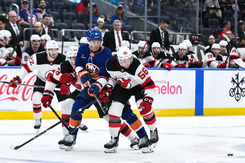 Nov 9, 2024; Elmont, New York, USA; New York Islanders left wing Pierre Engvall (18) competes for the puck against New Jersey Devils defenseman Luke Hughes (43) and New Jersey Devils left wing Erik Haula (56) during the second period at UBS Arena. Mandatory Credit: John Jones-Imagn Images