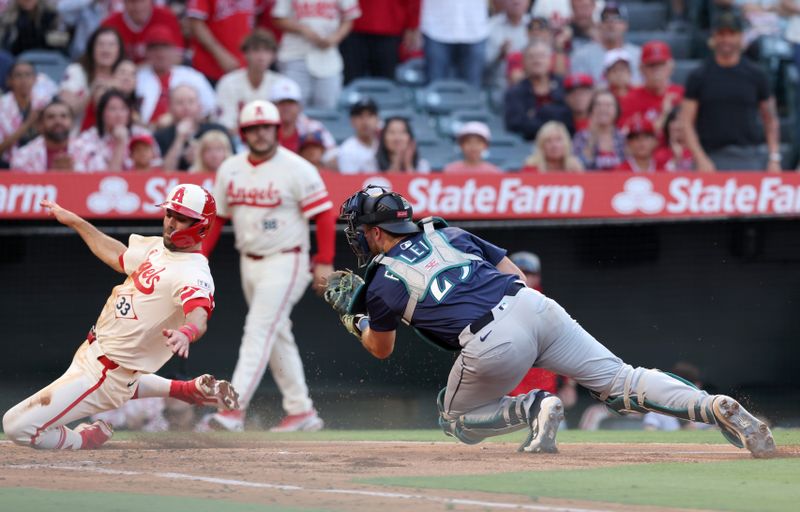 Jun 6, 2025; Anaheim, California, USA; Los Angeles Angels outfielder Chris Taylor (33) scores against Seattle Mariners catcher Cal Raleigh (29) during the third inning at Angel Stadium. Mandatory Credit: Jason Parkhurst-Imagn Images