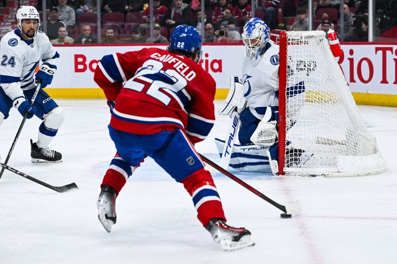 Apr 4, 2024; Montreal, Quebec, CAN; Montreal Canadiens right wing Cole Caufield (22) plays the puck near Tampa Bay Lightning goalie Matt Tomkins (90) during the third period at Bell Centre. Mandatory Credit: David Kirouac-USA TODAY Sports