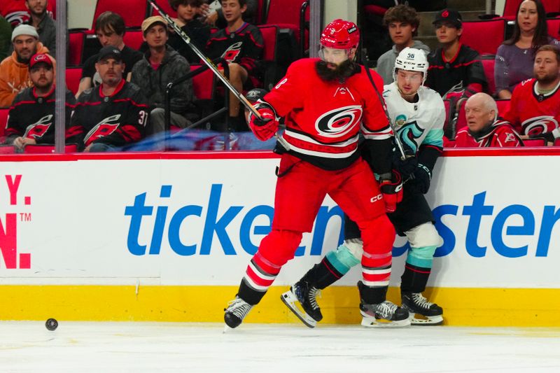 Oct 26, 2023; Raleigh, North Carolina, USA; Seattle Kraken right wing Kailer Yamamoto (56) and Carolina Hurricanes defenseman Brent Burns (8) watch the puck during the second period at PNC Arena. Mandatory Credit: James Guillory-USA TODAY Sports