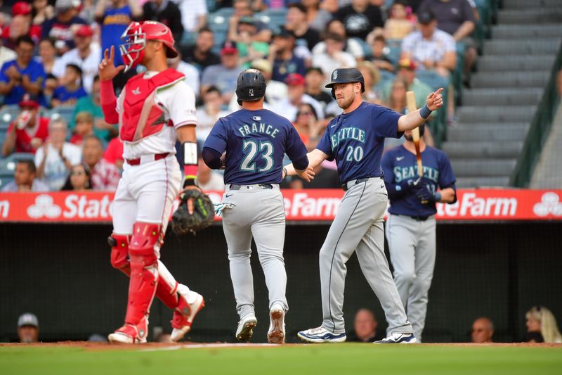 Jul 11, 2024; Anaheim, California, USA; Seattle Mariners first baseman Ty France (23) is greeted by right fielder Luke Raley (20) after scoring a run against the Los Angeles Angels during the first inning at Angel Stadium. Mandatory Credit: Gary A. Vasquez-USA TODAY Sports