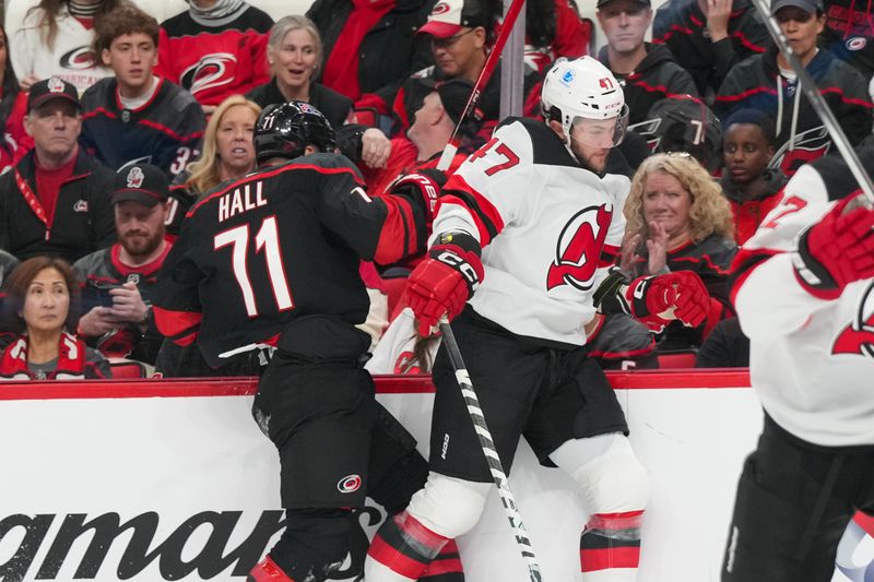 Oct 9, 2025; Raleigh, North Carolina, USA;  New Jersey Devils left wing Paul Cotter (47) checks Carolina Hurricanes left wing Taylor Hall (71) during the first period at Lenovo Center. Mandatory Credit: James Guillory-Imagn Images
