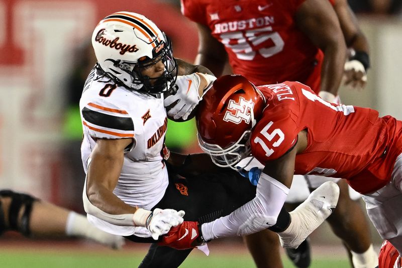 Nov 18, 2023; Houston, Texas, USA; Oklahoma State Cowboys running back Ollie Gordon II (0) is tackled by Houston Cougars defensive back Malik Fleming (15) during the fourth quarter at TDECU Stadium. Mandatory Credit: Maria Lysaker-USA TODAY Sports