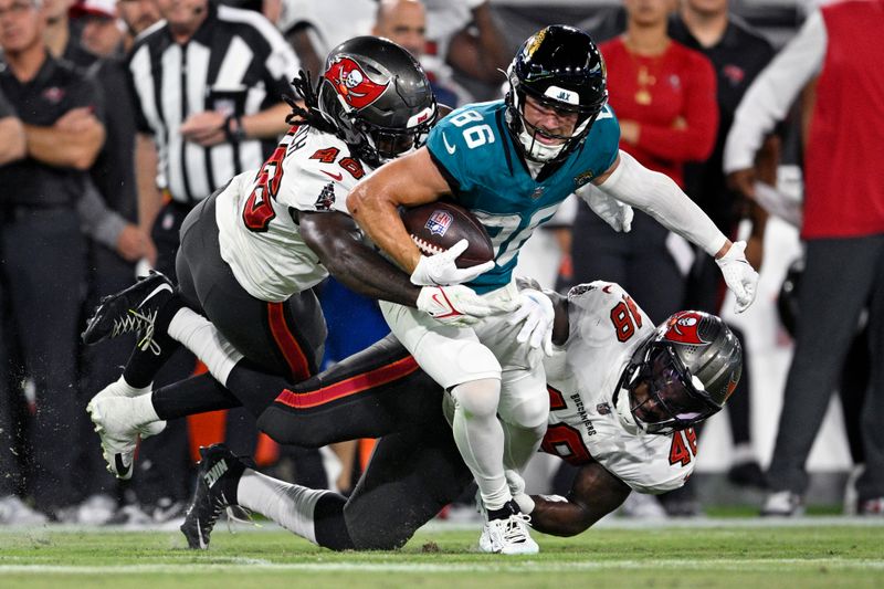 Jacksonville Jaguars wide receiver Austin Trammell (86) stopped after a reception by Tampa Bay Buccaneers linebacker Antonio Grier Jr., left, and linebacker Kalen DeLoach (46) during the second half of an NFL preseason football game, Saturday, Aug. 17, 2024, in Jacksonville, Fla. (AP Photo/Phelan M. Ebenhack)