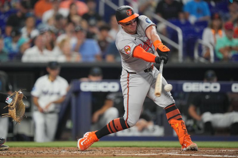 Jul 25, 2024; Miami, Florida, USA;  Baltimore Orioles catcher James McCann (27) hits an a single to score a run against the Miami Marlins in the second inning at loanDepot Park. Mandatory Credit: Jim Rassol-USA TODAY Sports