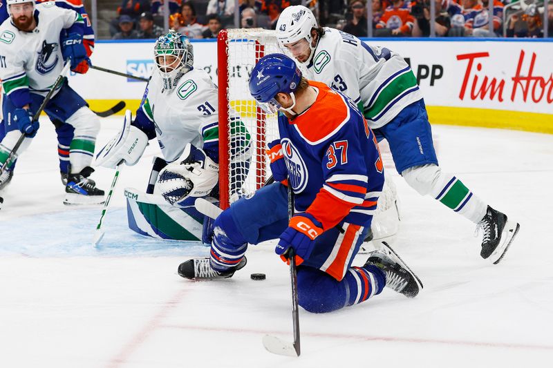 May 14, 2024; Edmonton, Alberta, CAN; Edmonton Oilers forward Warren Foegele (37) and Vancouver Canucks defensemen Quinn Hughes (43) battle for a loose puck during the third period in game four of the second round of the 2024 Stanley Cup Playoffs at Rogers Place. Mandatory Credit: Perry Nelson-USA TODAY Sports