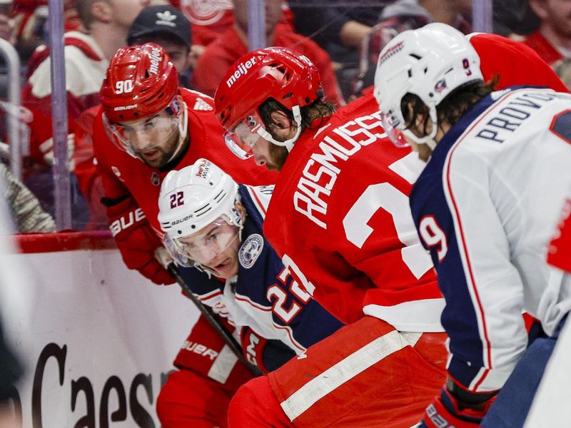 Mar 19, 2024; Detroit, Michigan, USA; Columbus Blue Jackets defenseman Jake Bean (22) and Detroit Red Wings center Michael Rasmussen (27) fight for control of the puck behind the net at Little Caesars Arena. Mandatory Credit: Brian Bradshaw Sevald-USA TODAY Sports