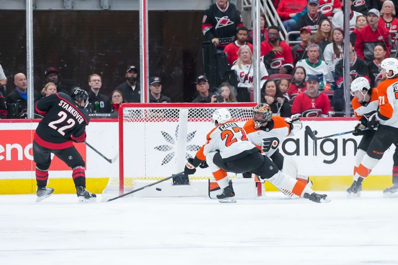 Oct 11, 2025; Raleigh, North Carolina, USA;  Carolina Hurricanes center Logan Stankoven (22) scores a goal past Philadelphia Flyers goaltender Samuel Ersson (33) and Philadelphia Flyers left wing Noah Cates (27) during the second period at Lenovo Center. Mandatory Credit: James Guillory-Imagn Images