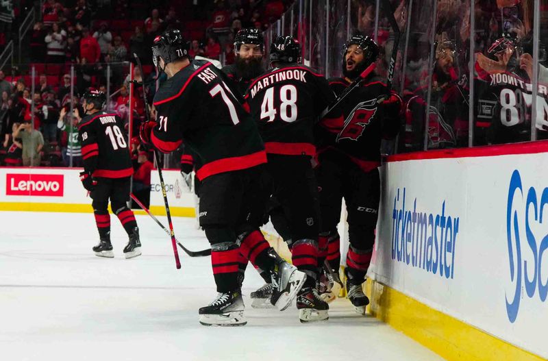 Nov 22, 2023; Raleigh, North Carolina, USA; Carolina Hurricanes defenseman Jalen Chatfield (5) left wing Jordan Martinook (48) defenseman Brent Burns (8) and right wing Jesper Fast (71) celebrate their victory against the Edmonton Oilers at PNC Arena. Mandatory Credit: James Guillory-USA TODAY Sports