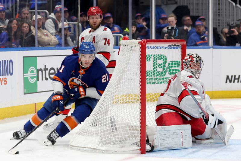 Jan 25, 2025; Elmont, New York, USA; New York Islanders center Kyle Palmieri (21) controls the puck against Carolina Hurricanes defenseman Jaccob Slavin (74) and goaltender Pyotr Kochetkov (52) during the third period at UBS Arena. Mandatory Credit: Brad Penner-Imagn Images