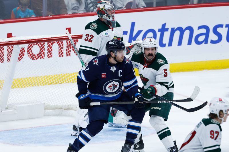 Oct 13, 2024; Winnipeg, Manitoba, CAN;  Winnipeg Jets forward Adam Lowry (17) jostles for position withMinnesota Wild defenseman Jake Middleton (5) during the third period at Canada Life Centre. Mandatory Credit: Terrence Lee-Imagn Images