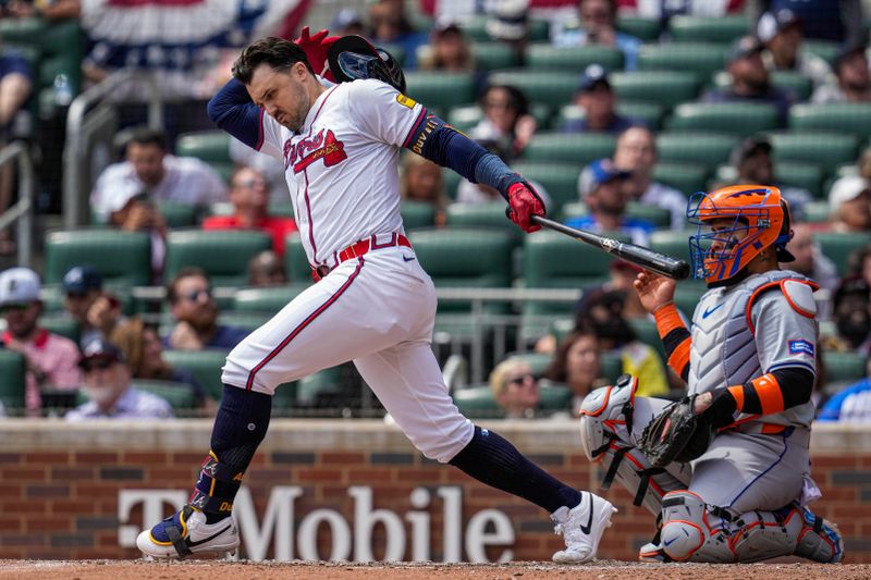 Apr 11, 2024; Cumberland, Georgia, USA; Atlanta Braves catcher Travis d'Arnaud (16) tries to hold on to his helmet after a swing at a pitch against the New York Mets during the sixth inning at Truist Park. Mandatory Credit: Dale Zanine-USA TODAY Sports