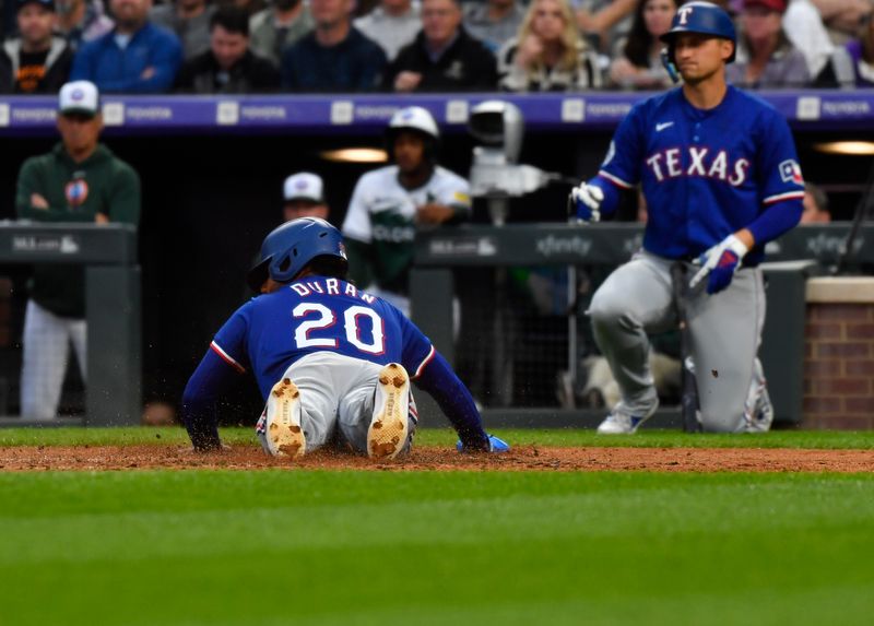 May 11, 2024; Denver, Colorado, USA; Texas Rangers designated hitter Ezequiel Duran (20) slides in at home to score from third against the Colorado Rockies during the fifth inning at Coors Field. Mandatory Credit: John Leyba-USA TODAY Sports