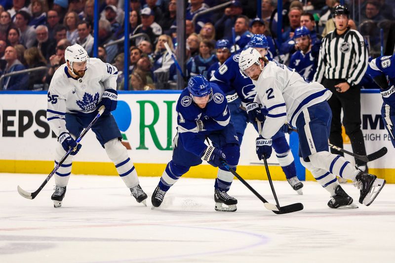 Feb 25, 2026; Tampa, Florida, USA; Tampa Bay Lightning forward Brayden Point (21) and Toronto Maple Leafs defenseman Simon Benoit (2) battle for the puck during the first period at Benchmark International Arena. Mandatory Credit: Morgan Tencza-Imagn Images