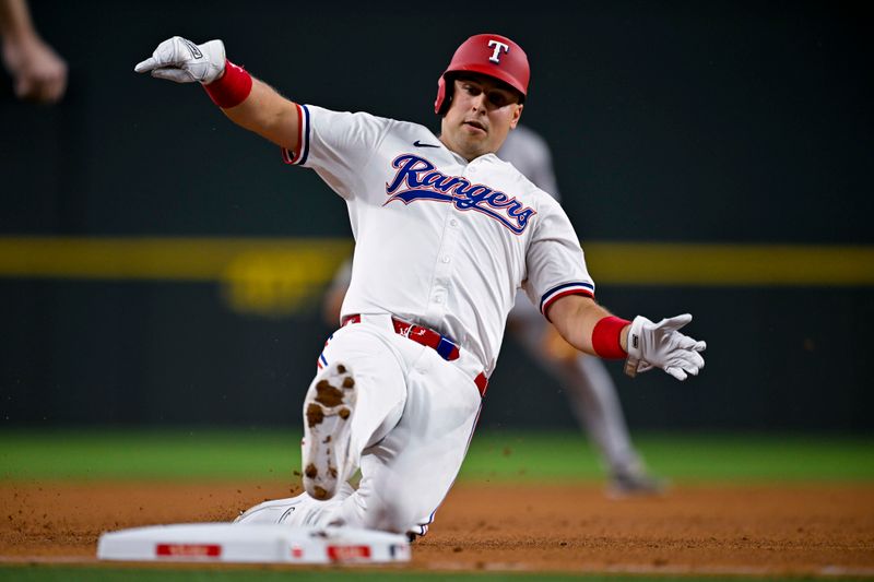 Aug 5, 2024; Arlington, Texas, USA; Texas Rangers first baseman Nathaniel Lowe (30) slides into third base during the fifth inning against the Houston Astros at Globe Life Field. Mandatory Credit: Jerome Miron-USA TODAY Sports