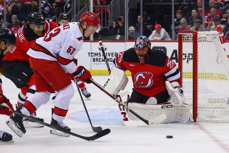 Nov 21, 2024; Newark, New Jersey, USA; Carolina Hurricanes right wing Jackson Blake (53) controls the puck while New Jersey Devils goaltender Jacob Markstrom (25) defends his net during the first period at Prudential Center. Mandatory Credit: Ed Mulholland-Imagn Images