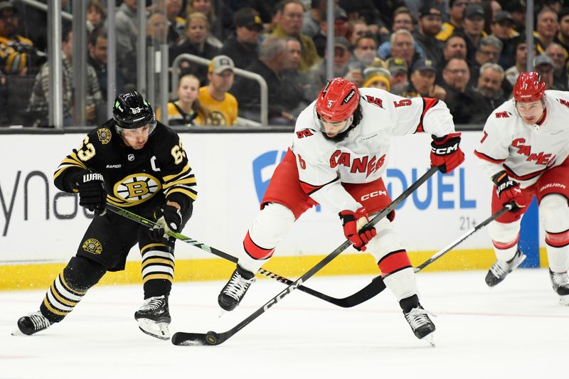 Apr 9, 2024; Boston, Massachusetts, USA; Boston Bruins left wing Brad Marchand (63) and Carolina Hurricanes defenseman Jalen Chatfield (5) battle for the puck during the first period at TD Garden. Mandatory Credit: Bob DeChiara-USA TODAY Sports