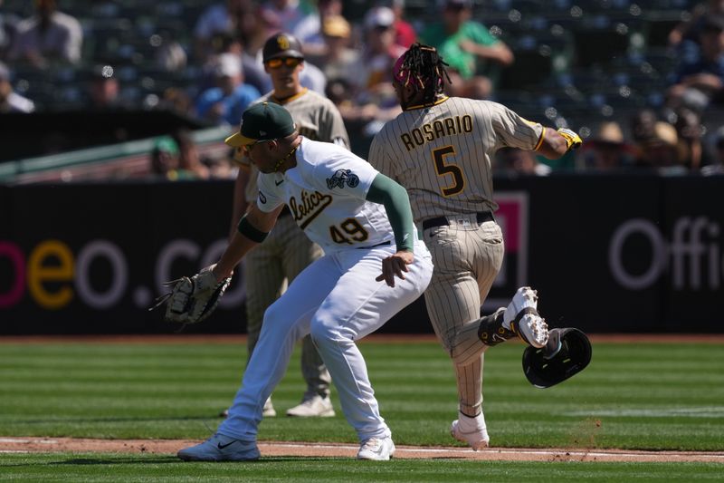 Sep 17, 2023; Oakland, California, USA; San Diego Padres third baseman Eguy Rosario (5) avoids a tag by Oakland Athletics first baseman Ryan Noda (49) for an RBI single during the fourth inning at Oakland-Alameda County Coliseum. Mandatory Credit: Darren Yamashita-USA TODAY Sports