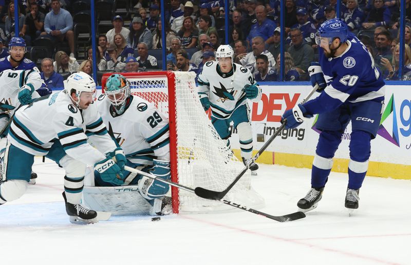 Oct 26, 2023; Tampa, Florida, USA; Tampa Bay Lightning left wing Nicholas Paul (20) shoots as San Jose Sharks defenseman Kyle Burroughs (4) and goaltender Mackenzie Blackwood (29) defend during the first period at Amalie Arena. Mandatory Credit: Kim Klement Neitzel-USA TODAY Sports