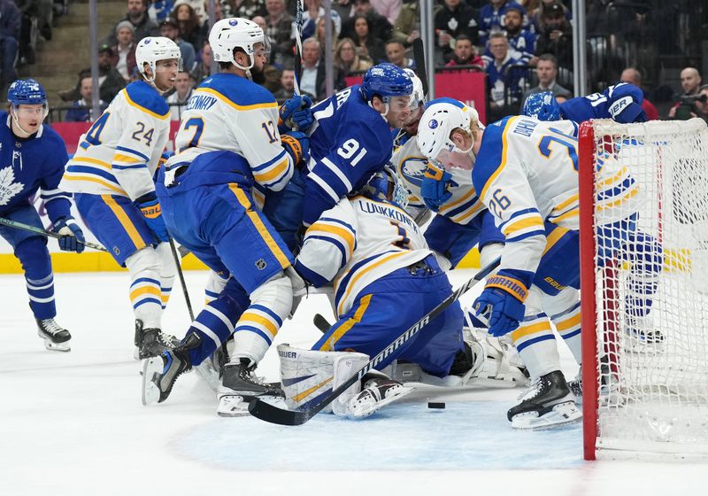 Mar 6, 2024; Toronto, Ontario, CAN; Toronto Maple Leafs center John Tavares (91) battles for the puck with Buffalo Sabres left wing Jordan Greenway (12) in front of goaltender Ukko-Pekka Luukkonen (1) during the third period at Scotiabank Arena. Mandatory Credit: Nick Turchiaro-USA TODAY Sports