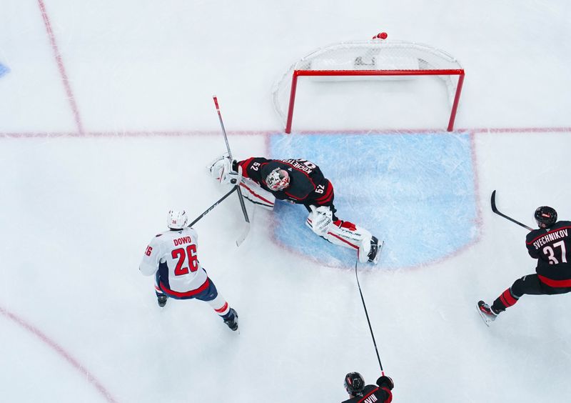 Nov 3, 2024; Raleigh, North Carolina, USA;  Carolina Hurricanes goaltender Pyotr Kochetkov (52) stops the shot by Washington Capitals center Nic Dowd (26) during the first period at Lenovo Center. Mandatory Credit: James Guillory-Imagn Images