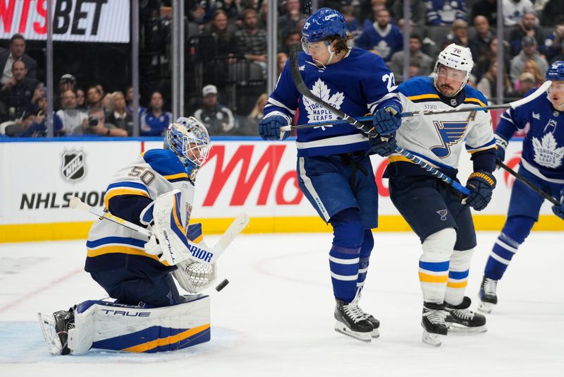 Oct 24, 2024; Toronto, Ontario, CAN; St. Louis Blues goaltender Jordan Binnington (50) makes a save as Toronto Maple Leafs forward Matthew Knies (23) battles with St. Louis Blues defenseman Justin Faulk (72) for position during the first period at Scotiabank Arena. Mandatory Credit: John E. Sokolowski-Imagn Images