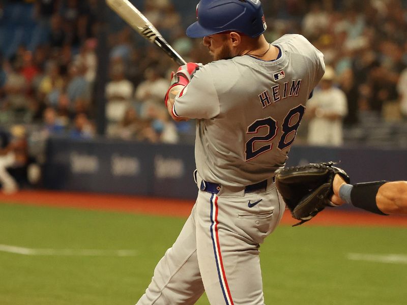 Apr 2, 2024; St. Petersburg, Florida, USA; Texas Rangers catcher Jonah Heim (28) hits a RBI single during the ninth inning against the Tampa Bay Rays at Tropicana Field. Mandatory Credit: Kim Klement Neitzel-USA TODAY Sports