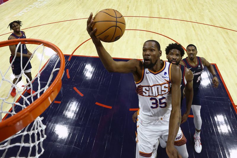 PHILADELPHIA, PENNSYLVANIA - NOVEMBER 04: Kevin Durant #35 of the Phoenix Suns shoots a lay up past Joel Embiid #21 and De'Anthony Melton #8 of the Philadelphia 76ers during the third quarter at the Wells Fargo Center on November 04, 2023 in Philadelphia, Pennsylvania. NOTE TO USER: User expressly acknowledges and agrees that, by downloading and or using this photograph, User is consenting to the terms and conditions of the Getty Images License Agreement. (Photo by Tim Nwachukwu/Getty Images)