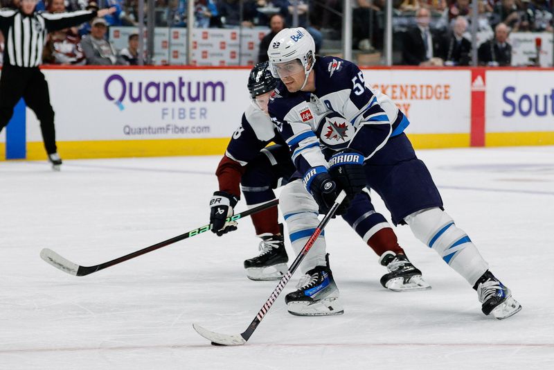 Apr 13, 2024; Denver, Colorado, USA; Winnipeg Jets center Mark Scheifele (55) controls the puck ahead of Colorado Avalanche defenseman Cale Makar (8) in the first period at Ball Arena. Mandatory Credit: Isaiah J. Downing-USA TODAY Sports