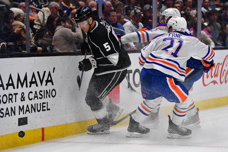 Dec 30, 2023; Los Angeles, California, USA; Los Angeles Kings defenseman Andreas Englund (5) plays for the puck against Edmonton Oilers left wing Adam Erne (21) during the first period at Crypto.com Arena. Mandatory Credit: Gary A. Vasquez-USA TODAY Sports