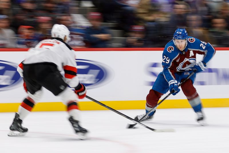 Feb 26, 2025; Denver, Colorado, USA; Colorado Avalanche center Nathan MacKinnon (29) controls the puck as New Jersey Devils defenseman Brenden Dillon (5) defends in the second period at Ball Arena. Mandatory Credit: Isaiah J. Downing-Imagn Images