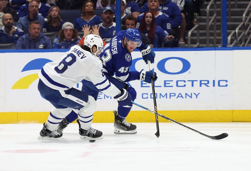 Apr 9, 2025; Tampa, Florida, USA; Tampa Bay Lightning defenseman Darren Raddysh (43) skates with the puck as Toronto Maple Leafs defenseman Chris Tanev (8) defends during the third period at Amalie Arena. Mandatory Credit: Kim Klement Neitzel-Imagn Images