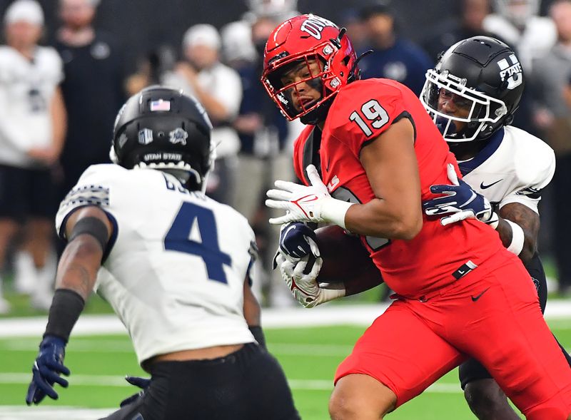 Oct 16, 2021; Paradise, Nevada, USA; UNLV Rebels tight end Kaleo Ballungay (19) looks to absorb the hit from Utah State Aggies safety Shaq Bond (4) as he is tackled by Utah State Aggies safety Ike Larsen (19) during the first half at Allegiant Stadium. Mandatory Credit: Stephen R. Sylvanie-USA TODAY Sports