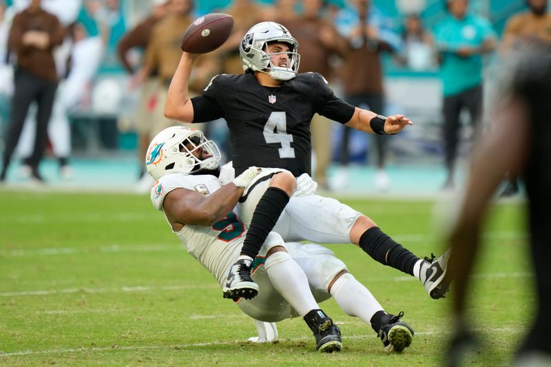 Miami Dolphins defensive tackle Christian Wilkins (94) takes down Las Vegas Raiders quarterback Aidan O'Connell (4) during the second half of an NFL football game, Sunday, Nov. 19, 2023, in Miami Gardens, Fla. O'Connell three the ball which was intercepted by Miami Dolphins linebacker Jaelan Phillips. (AP Photo/Wilfredo Lee)