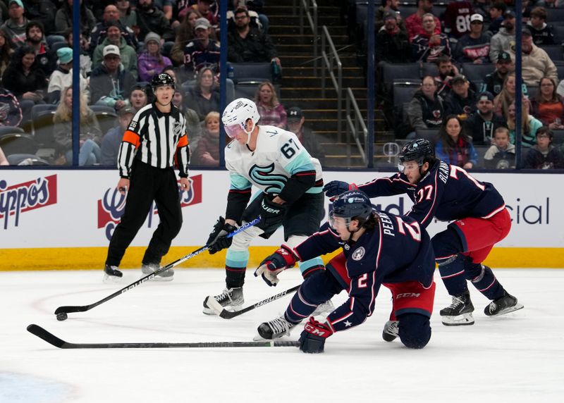 Mar 3, 2023; Columbus, Ohio, USA;  Seattle Kraken center Morgan Geekie (67) controls the puck while Columbus Blue Jackets defenseman Andrew Peeke (2) and Columbus Blue Jackets defenseman Nick Blankenburg (77) defends during the first period at Nationwide Arena. Mandatory Credit: Jason Mowry-USA TODAY Sports