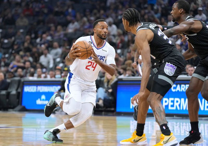 SACRAMENTO, CALIFORNIA - OCTOBER 22: Norman Powell #24 of the LA Clippers drives past De'Aaron Fox #5 and Harrison Barnes #40 of the Sacramento Kings during the first quarter of the game at Golden 1 Center on October 22, 2022 in Sacramento, California. NOTE TO USER: User expressly acknowledges and agrees that, by downloading and or using this photograph, User is consenting to the terms and conditions of the Getty Images License Agreement. (Photo by Thearon W. Henderson/Getty Images)