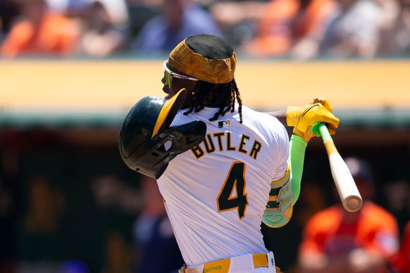 Jul 24, 2024; Oakland, California, USA; Oakland Athletics right fielder Lawrence Butler (4) loses his helmet as he swings and misses against the Houston Astros during the second inning at Oakland-Alameda County Coliseum. Mandatory Credit: D. Ross Cameron-USA TODAY Sports