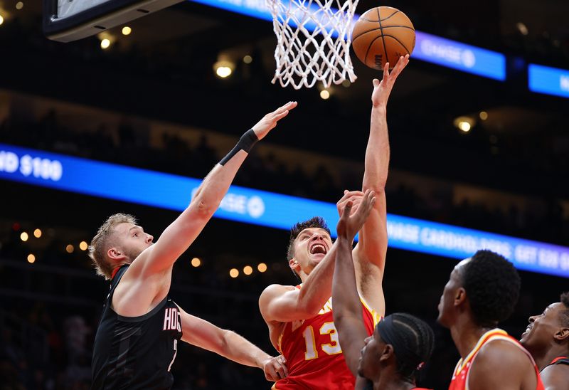 ATLANTA, GEORGIA - FEBRUARY 10:  Bogdan Bogdanovic #13 of the Atlanta Hawks attacks the basket against Jock Landale #2 and Aaron Holiday #0 of the Houston Rockets during the first quarter at State Farm Arena on February 10, 2024 in Atlanta, Georgia.  NOTE TO USER: User expressly acknowledges and agrees that, by downloading and/or using this photograph, user is consenting to the terms and conditions of the Getty Images License Agreement.  (Photo by Kevin C. Cox/Getty Images)