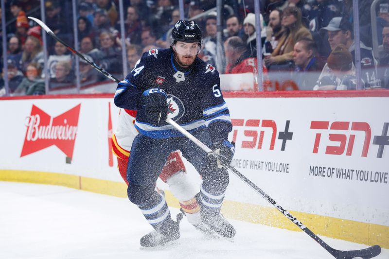 Jan 26, 2025; Winnipeg, Manitoba, CAN;  Winnipeg Jets defenseman Dylan Samberg (54) looks to make a pass against the Calgary Flames during the first period at Canada Life Centre. Mandatory Credit: Terrence Lee-Imagn Images