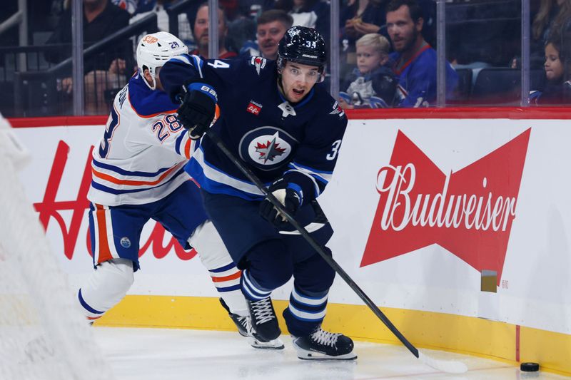 Sep 23, 2025; Winnipeg, Manitoba, CAN;  Winnipeg Jets defenseman Ville Heinola (34) skates away from Edmonton Oilers forward Quinn Hutson (28) during the first period at Canada Life Centre. Mandatory Credit: Terrence Lee-Imagn Images