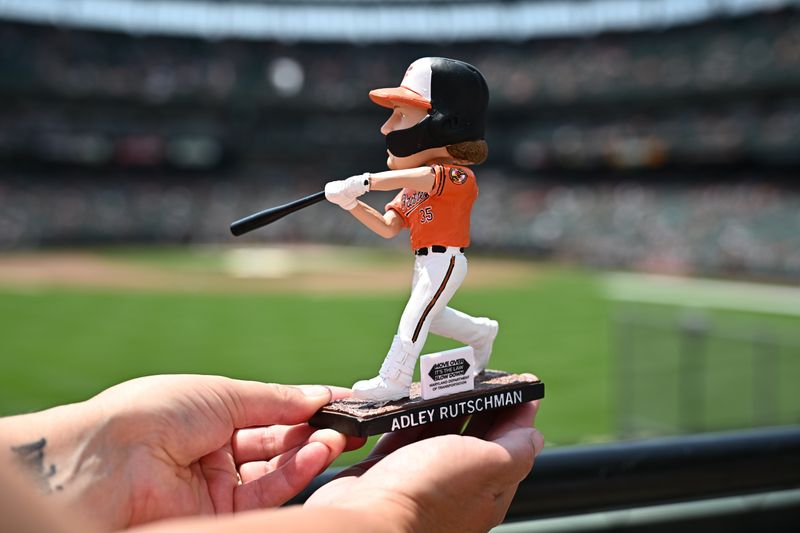 Jul 28, 2024; Baltimore, Maryland, USA;  A fan displays the Baltimore Orioles catcher Adley Rutschman (35) bobblehead before the game between the Baltimore Orioles and the San Diego Padres at Oriole Park at Camden Yards. Mandatory Credit: James A. Pittman-USA TODAY Sports