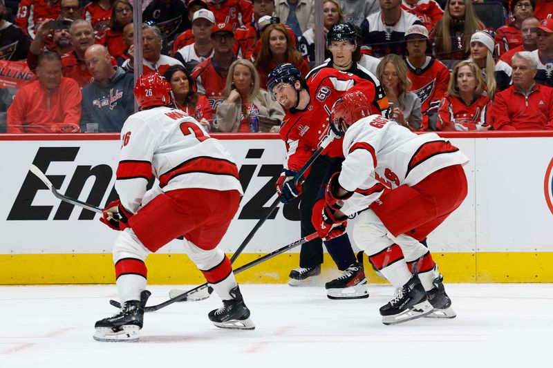 May 6, 2025; Washington, District of Columbia, USA; Washington Capitals right wing Ryan Leonard (9) shoots the puck as /Carolina Hurricanes defenseman Shayne Gostisbehere (4) and Hurricanes defenseman Sean Walker (26) defend in the first period in game one of the second round of the 2025 Stanley Cup Playoffs at Capital One Arena. Mandatory Credit: Geoff Burke-Imagn Images