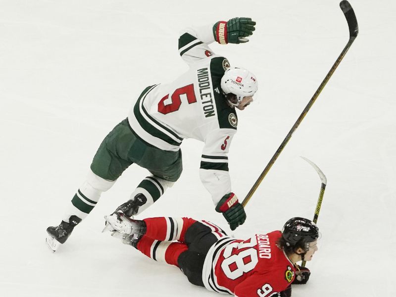 Jan 26, 2025; Chicago, Illinois, USA; Chicago Blackhawks center Connor Bedard (98) and Minnesota Wild defenseman Jake Middleton (5) go for the puck during the third period at United Center. Mandatory Credit: David Banks-Imagn Images