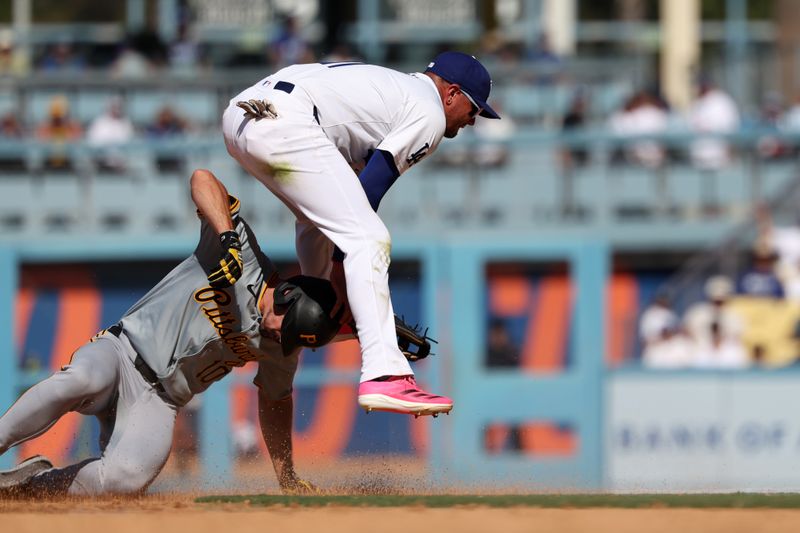 Aug 11, 2024; Los Angeles, California, USA;  Los Angeles Dodgers shortstop Miguel Rojas (11) jumps over Pittsburgh Pirates left fielder Bryan Reynolds (10) to complete a double play during the tenth inning at Dodger Stadium. Mandatory Credit: Kiyoshi Mio-USA TODAY Sports