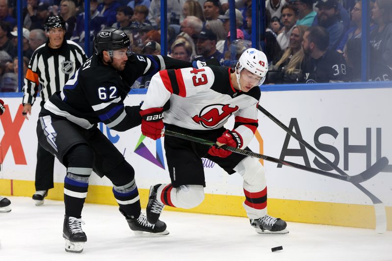 Oct 11, 2025; Tampa, Florida, USA; Tampa Bay Lightning center Jack Finley (62) defends against New Jersey Devils defenseman Luke Hughes (43) during the first period at Benchmark International Arena. Mandatory Credit: Kim Klement Neitzel-Imagn Images