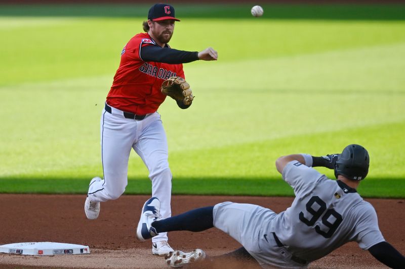 Apr 22, 2025; Cleveland, Ohio, USA; Cleveland Guardians second baseman Daniel Schneemann (10) turns a double play beside New York Yankees right fielder Aaron Judge (99) in the first inning at Progressive Field. Mandatory Credit: David Richard-Imagn Images